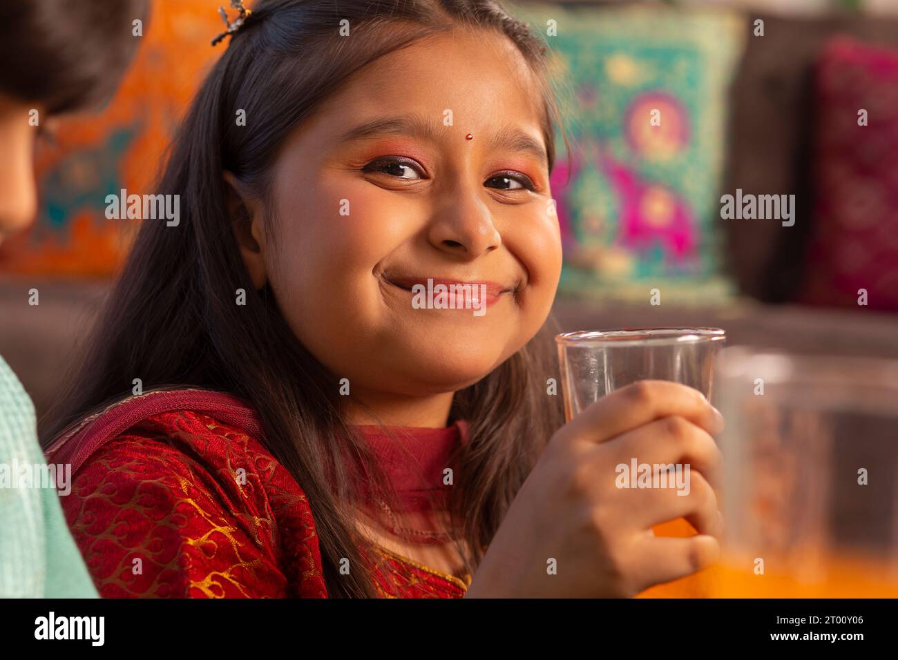 Nahporträt eines lächelnden Mädchens, das Orangensaft trinkt Stockfoto