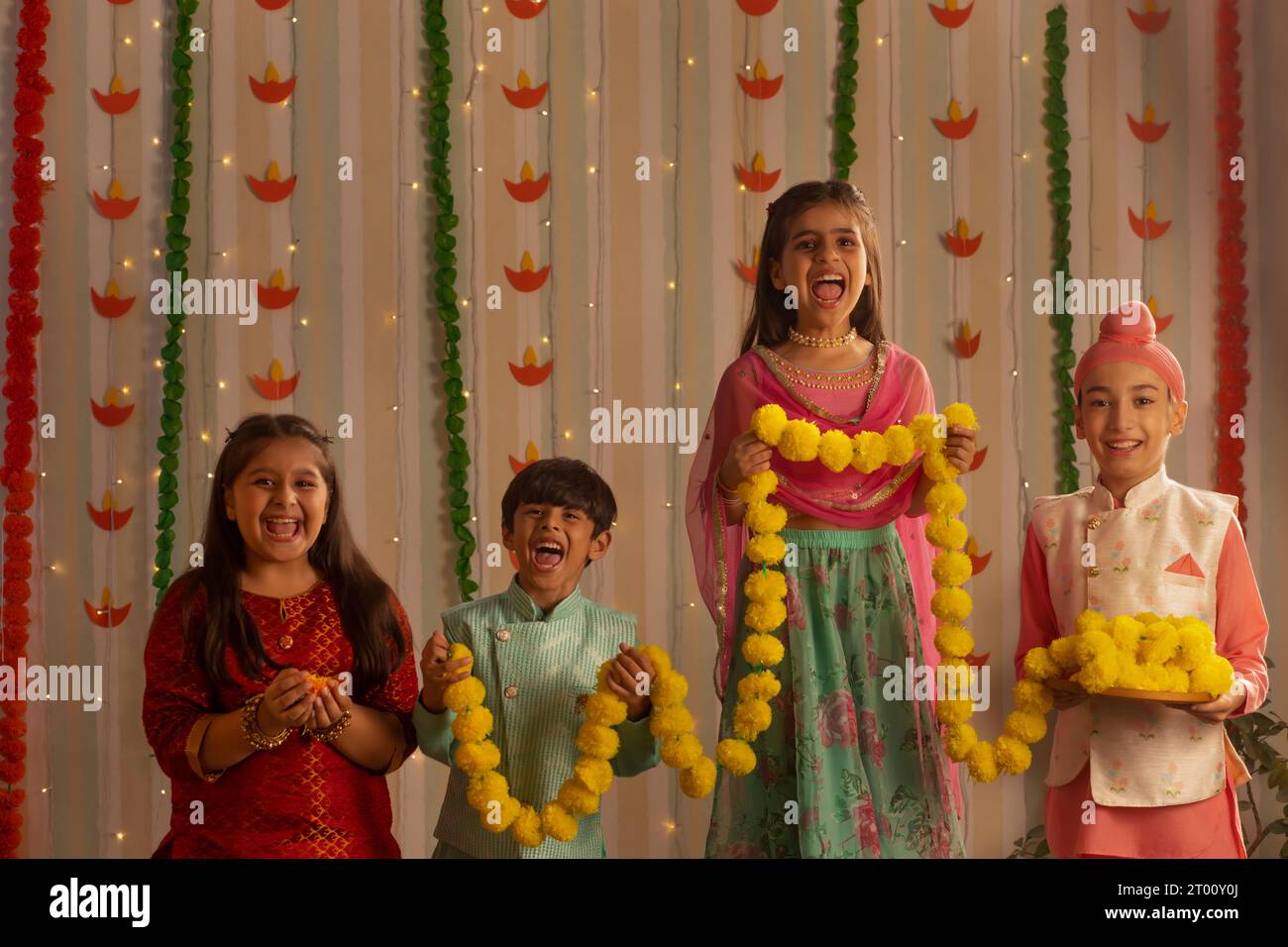 Kinder dekorieren Haus mit Blumengirlande anlässlich von Diwali Stockfoto