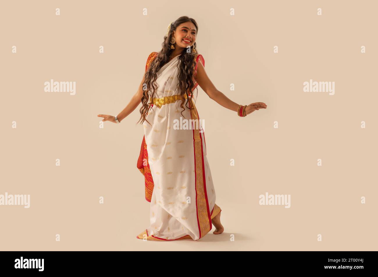 Porträt einer bengalischen Frau in traditionellem Outfit, tanzt vor weißem Hintergrund anlässlich von Durga Puja Stockfoto