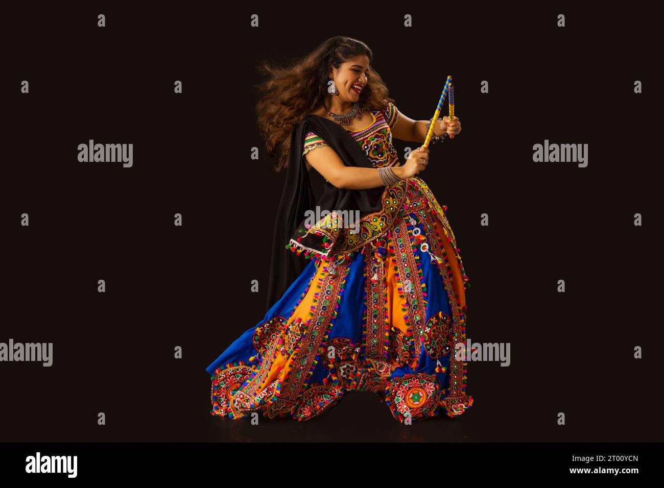 Gujarati-Frau tanzt mit Dandiya-Sticks auf einem klatschigen Hintergrund, während Navratri-Feiern Stockfoto