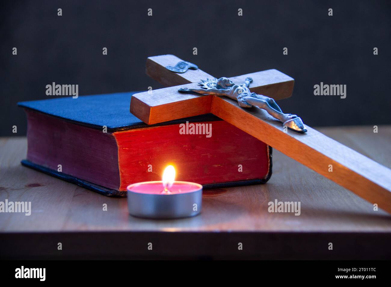 Heilige Bibel mit Kreuz und Kerzenflamme Stockfoto