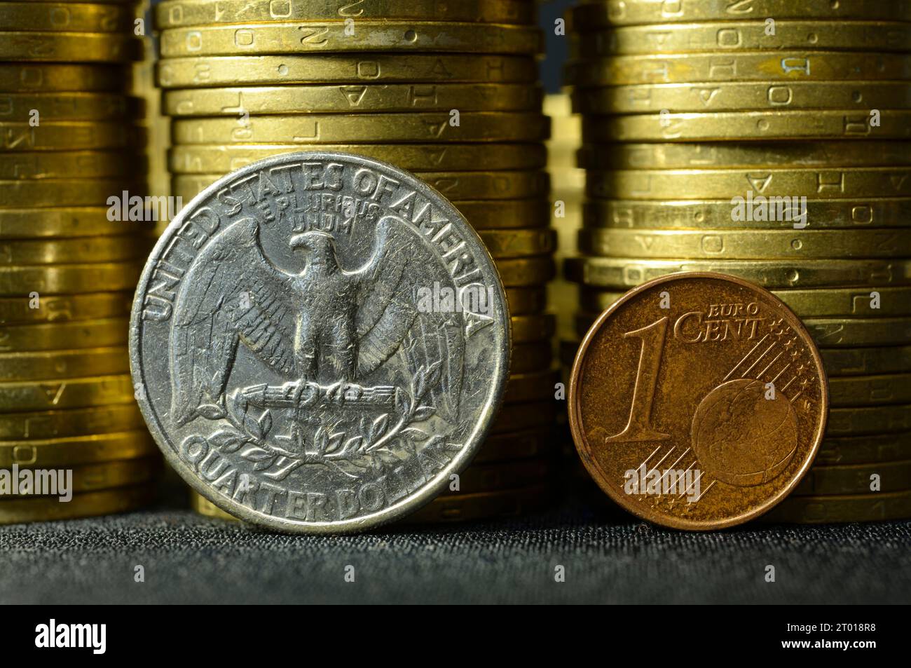Eine Vierteldollar-Münze und eine Euro-Cent-Münze, die an den Rändern vor den Münzstapeln platziert wird. Stockfoto