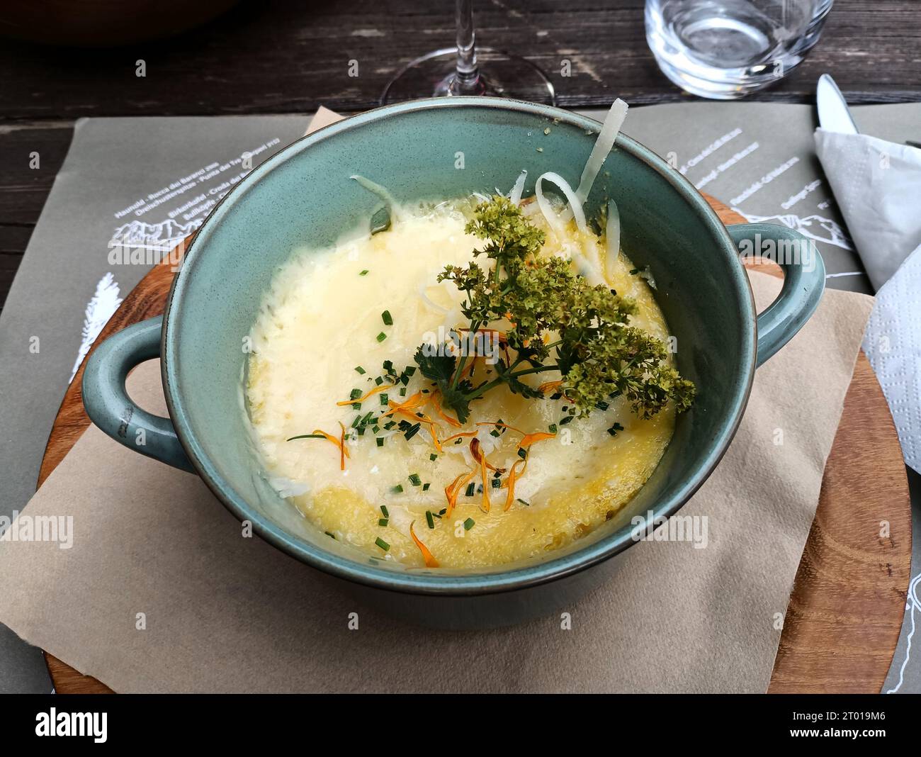 Ein appetitliches und sehr heißes Berggericht auf Basis von Polenta und Bergkäse garniert mit lokalen Kräutern Stockfoto