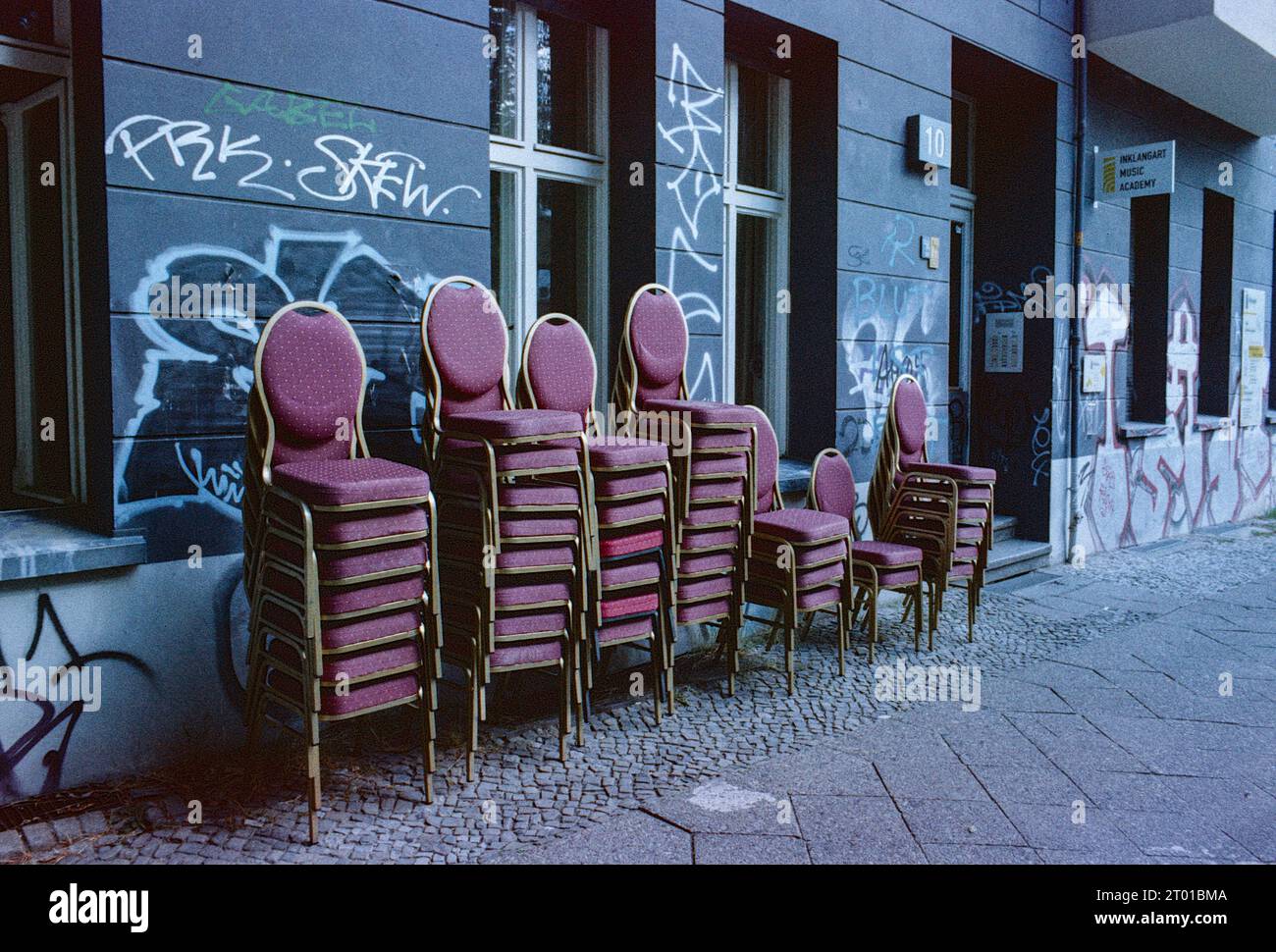 Stühle für das Publikum gleich draußen, auf dem Bürgersteig, der InKlangArt Music Academy. Berlin, Deutschland. Bild auf analogem, altem Kodak Film. Stockfoto