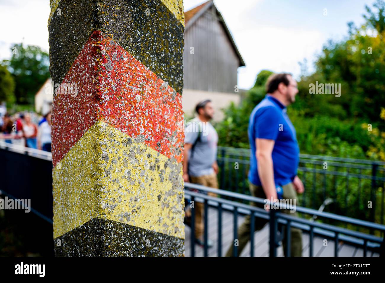 TAG DER DEUTSCHEN EINHEIT im DEUTSCH-DEUTSCHEN MUSEUM MÖDLAREUTH 03/10/2023 - Mödlareuth: Tag der Deutschen Einheit im Deutsch-Deutschen Museum zwischen Bayern und Thüringen in Mödlareuth am 3. Oktober 2023. Besucher laufen über eine Brücke hinter einem Grenzpfahl./                         *** TAG DER DEUTSCHEN EINHEIT IM DEUTSCHEN MUSEUM MÖDLAREUTH 03 10 2023 Mödlareuth Tag der Deutschen Einheit im Deutschen Museum zwischen Bayern und Thüringen in Mödlareuth am 3. Oktober 2023 laufen Besucher über eine Brücke hinter einem Grenzposten Credit: Imago/Alamy Live News Stockfoto