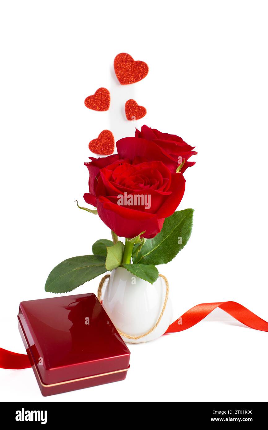 Rote Rosen in einer kleinen weißen Vase mit einer Schmuckschatulle, auf weißem Hintergrund, vertikale Fotografie Stockfoto