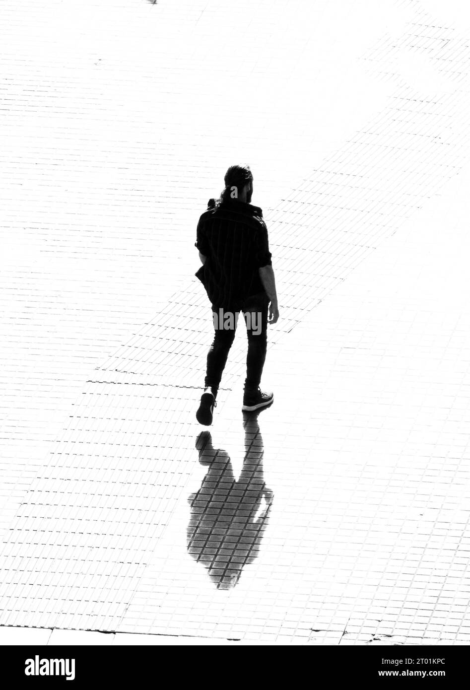 Rückansicht eines Mannes, der auf einem Bürgersteig läuft. Stockfoto