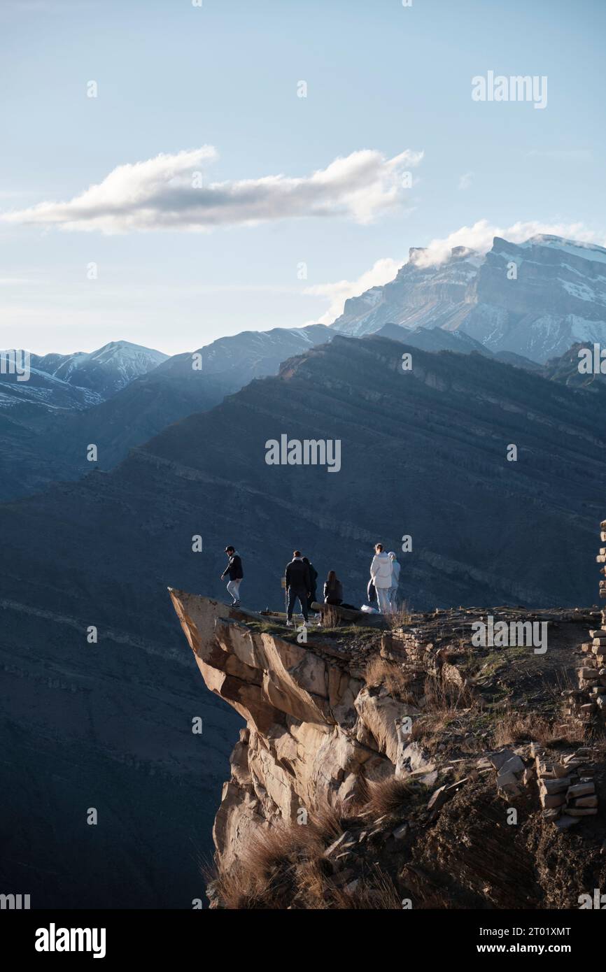 Russland. April 2023. Touristen genießen die sanfte Wärme des Sonnenuntergangs in den Bergen von der Klippe. Eine Gruppe unerschrockener Touristen steht auf der Zunge des Trolls in Dagestan, eingerahmt von kolossalen Eisbergen im Hintergrund. (Credit Image: © Daniil Kiselev/SOPA Images via ZUMA Press Wire) NUR REDAKTIONELLE VERWENDUNG! Nicht für kommerzielle ZWECKE! Stockfoto