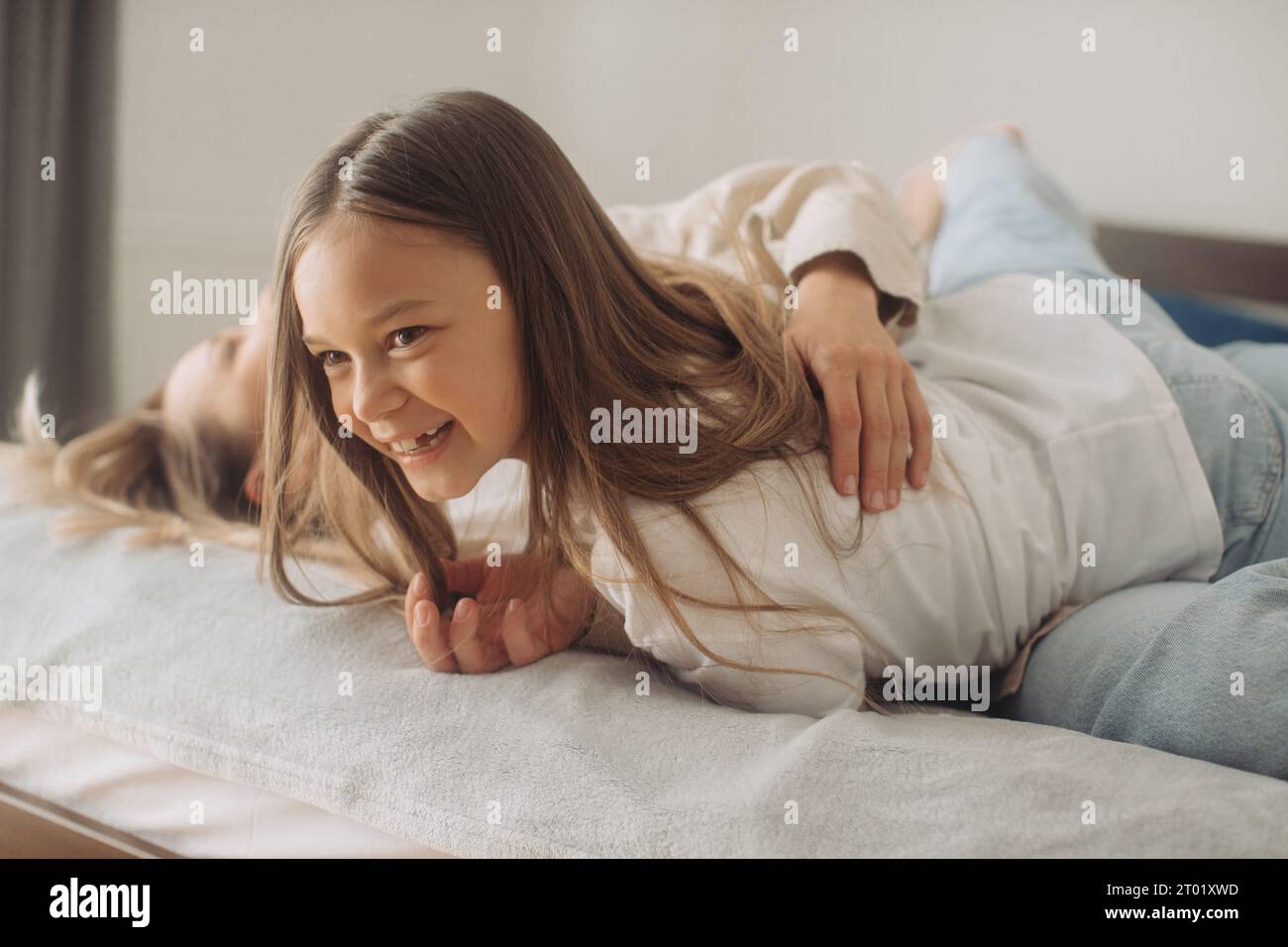 Nahaufnahme fröhliche Mutter Kuscheln kitzelt kleine süße Tochter, die im Bett liegt und morgens aufgewacht ist, fühlt sich glücklich und lebhaft an. Ausgeruhtes Kind sorglos Mama Porträt, Stockfoto