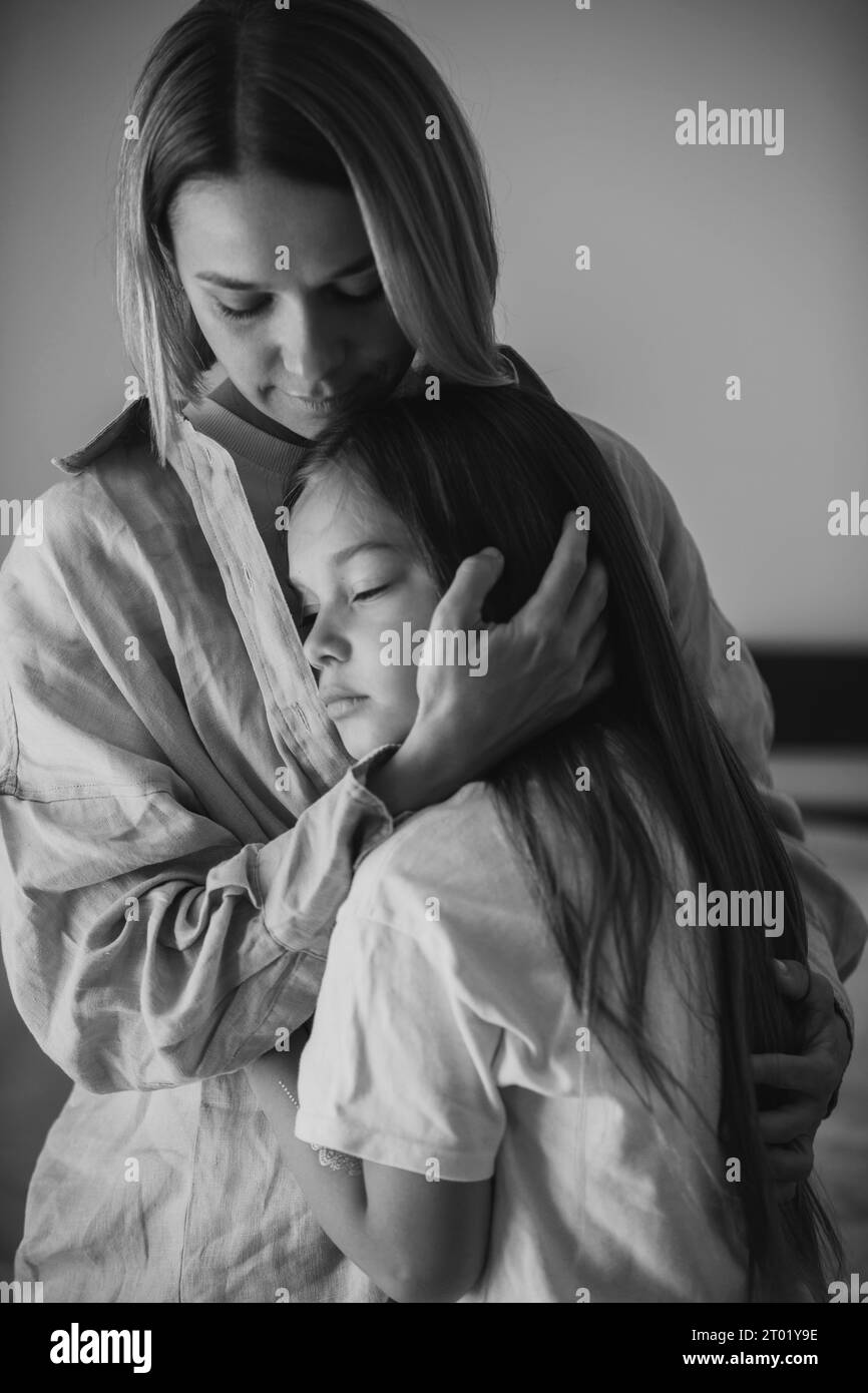 Muttertag. Eine kleine Tochter umarmt liebevoll ihre Mutter. BW-Foto. Stockfoto