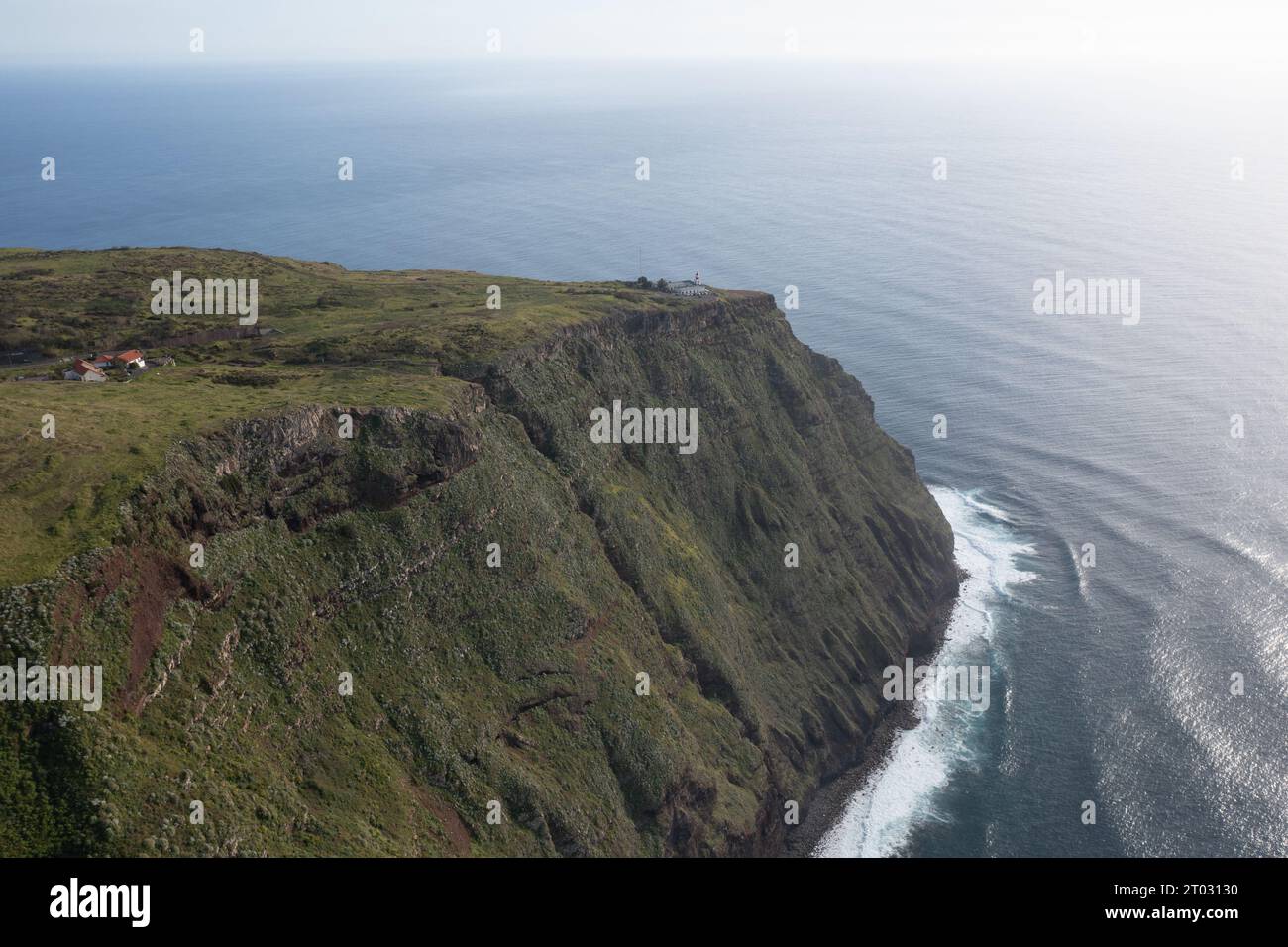 Großartiges Drohnenfoto von einer Klippe auf Madeira, wo ein Leuchtturm an der Spitze der Klippe steht und Schiffe vor der Landung warnt. Stockfoto