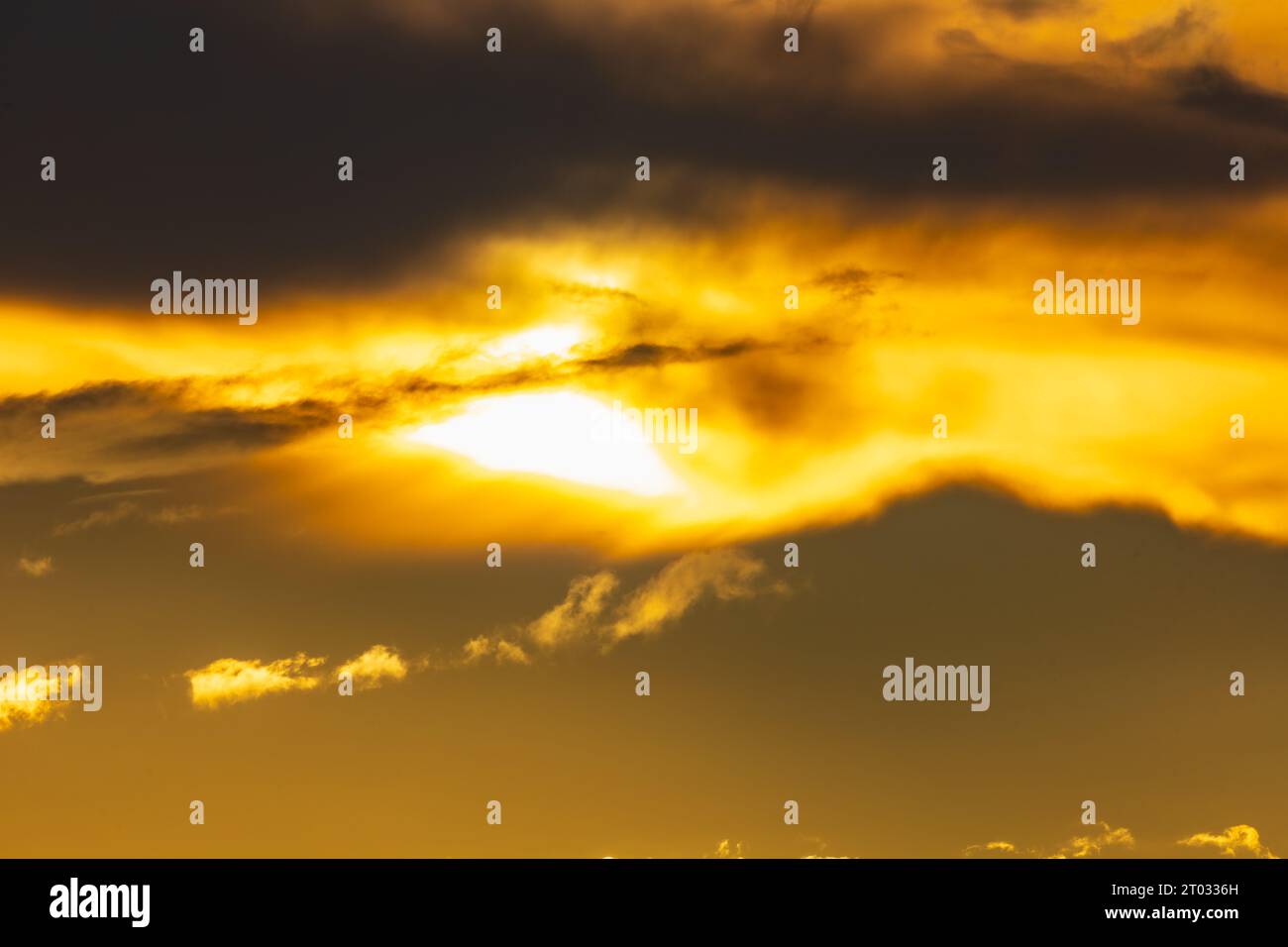 Wunderschöner, bewölkter gelber Sonnenuntergang mit gigantischer Sonne über großen Feldern und Bäumen, gesehen von einem 600-mm-Kameraobjektiv Stockfoto