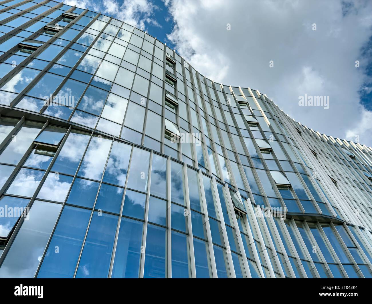 Fassade des Bürogebäudes mit Reflexen des blauen Himmels und der Wolken. Stockfoto