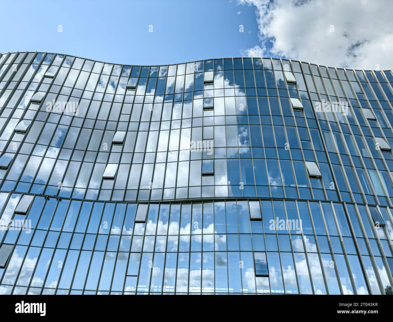 Glaswand eines modernen Gebäudes mit Reflexionen des Himmels und der Wolken. Stockfoto
