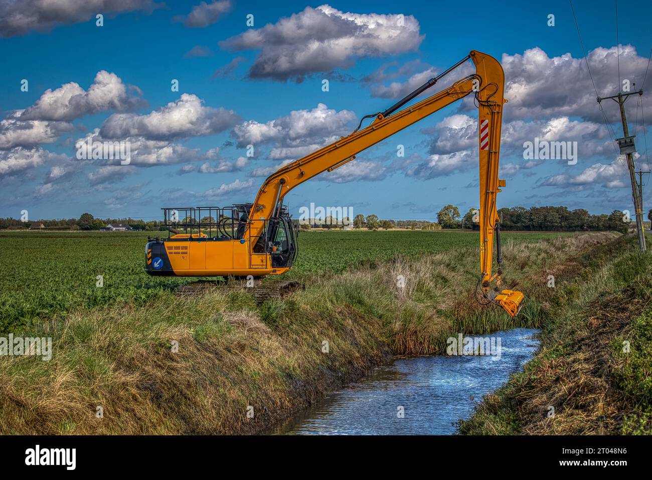Reed-Mähbagger zur Reinigung von Entwässerungsgräben in den Ebenen Gebieten des ländlichen Lincolnshire. Arbeiten unter herbstlich blauem Himmel unter idealen Bedingungen. Stockfoto