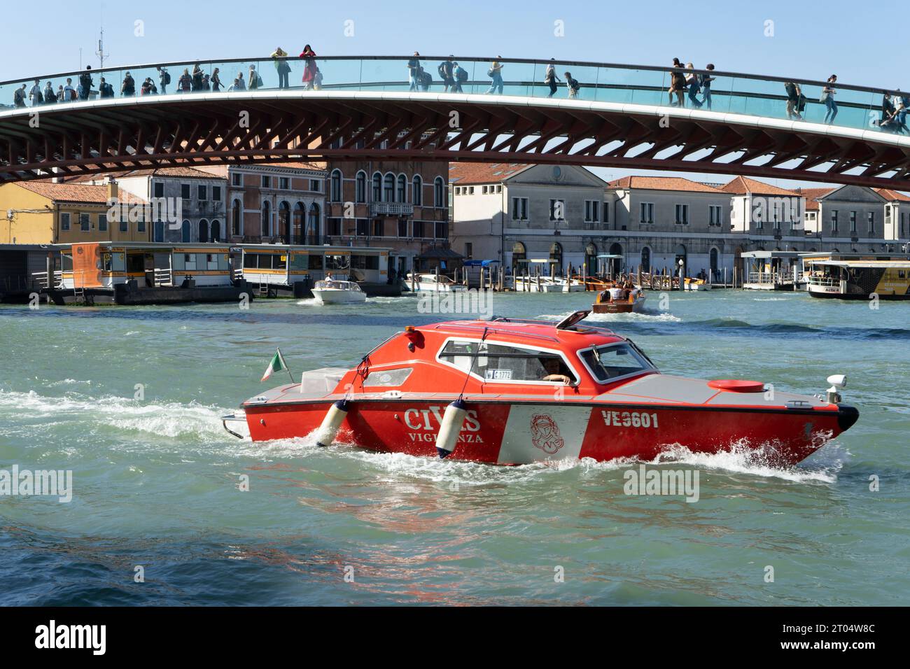 Ein Civis-Schnellboot, das an einem sonnigen Tag den Canal Grande und die Verfassungsbrücke in Venedig durchquert. Stockfoto Ein Civis-Schnellboot, das an einem sonnigen Tag den Canal Grande und die Verfassungsbrücke in Venedig durchquert. Stockfoto