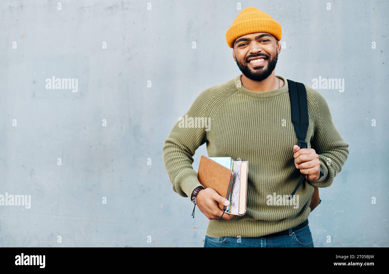 Rucksack, Bücher und Student oder Mann an einer Wand Hintergrund für Stipendien, Universität oder College Bildung und Lernen. Glückliches Porträt afrikas Stockfoto