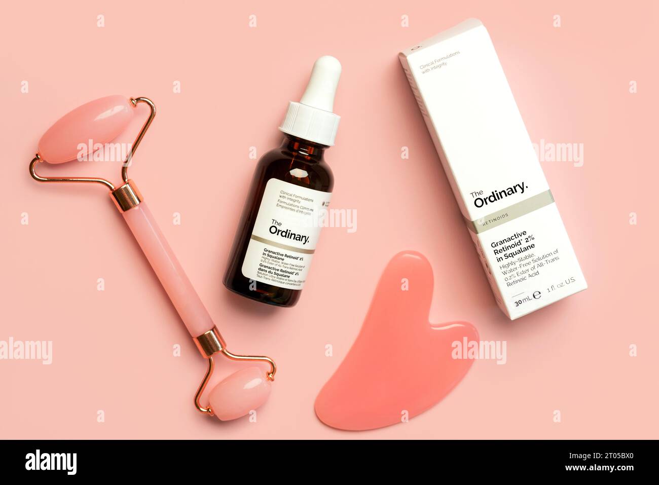 Die normale Hautpflegemarke. Nahaufnahme des gewöhnlichen Retinoidserums Granaktives Retinoid in Squalan- und Jade-Massagierwalze zur Hautpflege über rosa Stockfoto