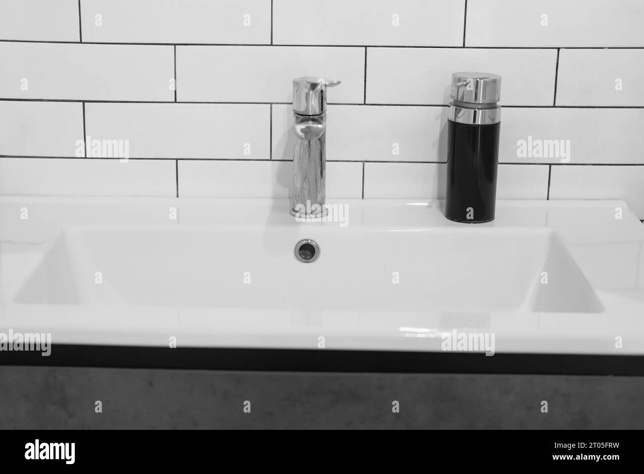 Modernes Waschbecken. Stilvolles weißes Waschbecken mit Wasserhähnen in moderner Einrichtung. Wasserhahn aus Chrommaterial. Haushaltsgeräte. Graues Badezimmer. Haushaltsgeräte Stockfoto