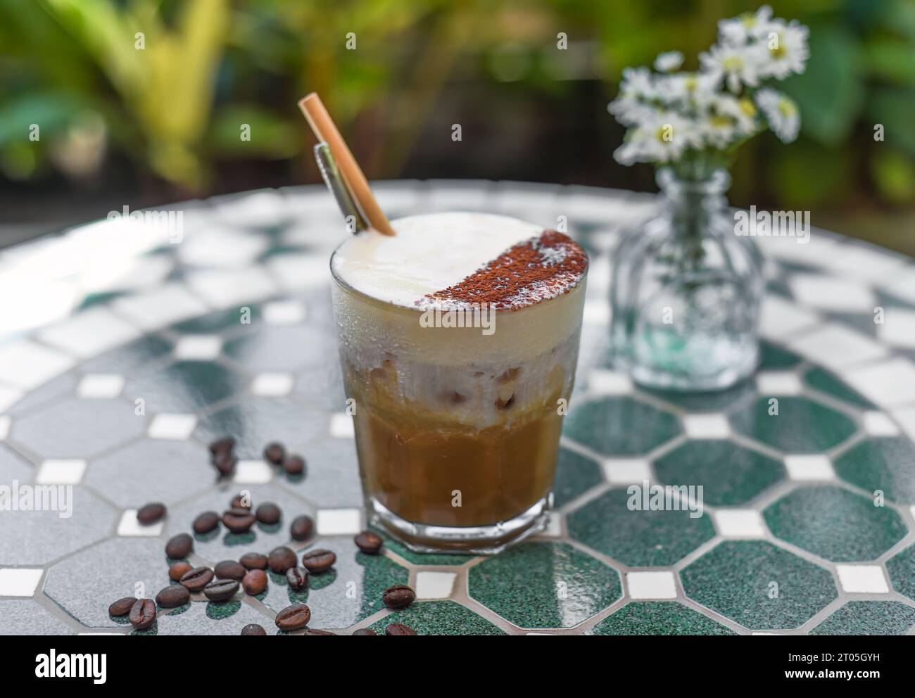 Vietnamesischer gesalzener Kaffee mit salziger Käsecreme (Ca phe muoi) gegen grüne Blätter Stockfoto