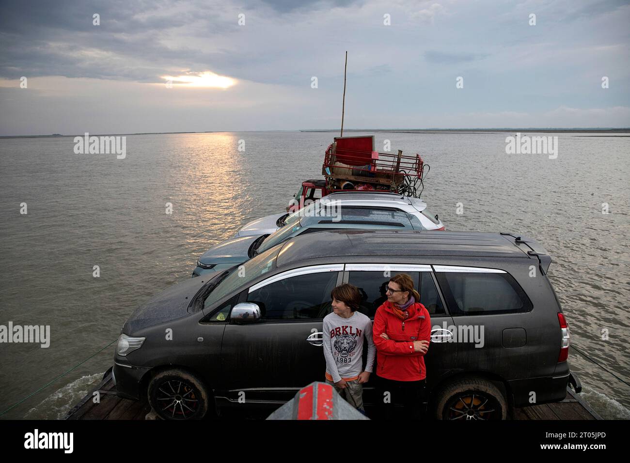 Touristen, Mutter und Sohn reisen mit einer kleinen hölzernen Fähre auf dem Brahmaputra River, transportieren Autos, Waren und Menschen zur Insel Majuli, Assam, Indien Stockfoto