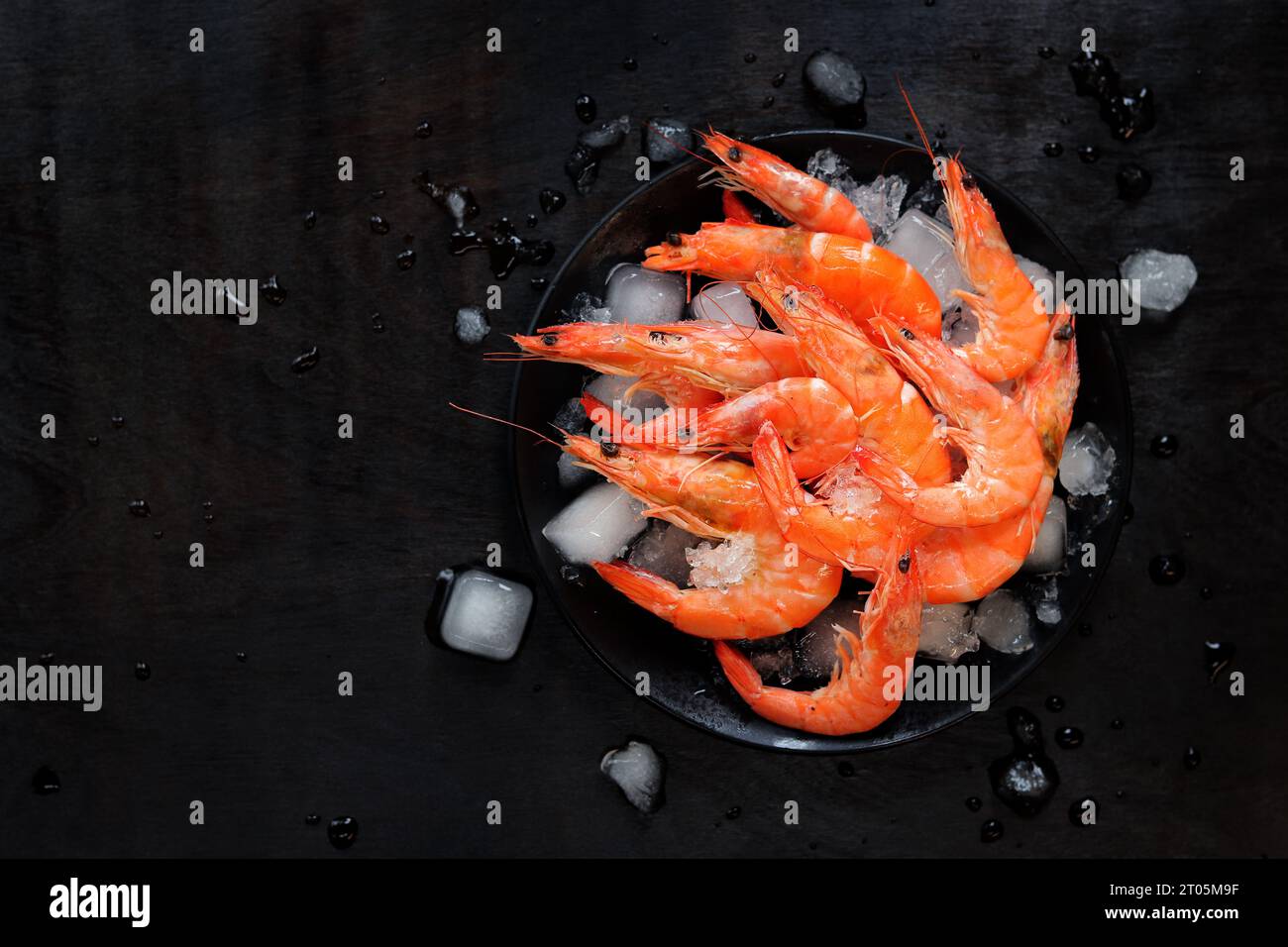 Frisch gekühlte Garnelen auf einem Teller mit Eis auf dunklem ... Frisch gekühlte Garnelen auf einem Teller mit Eis auf dunklem ...