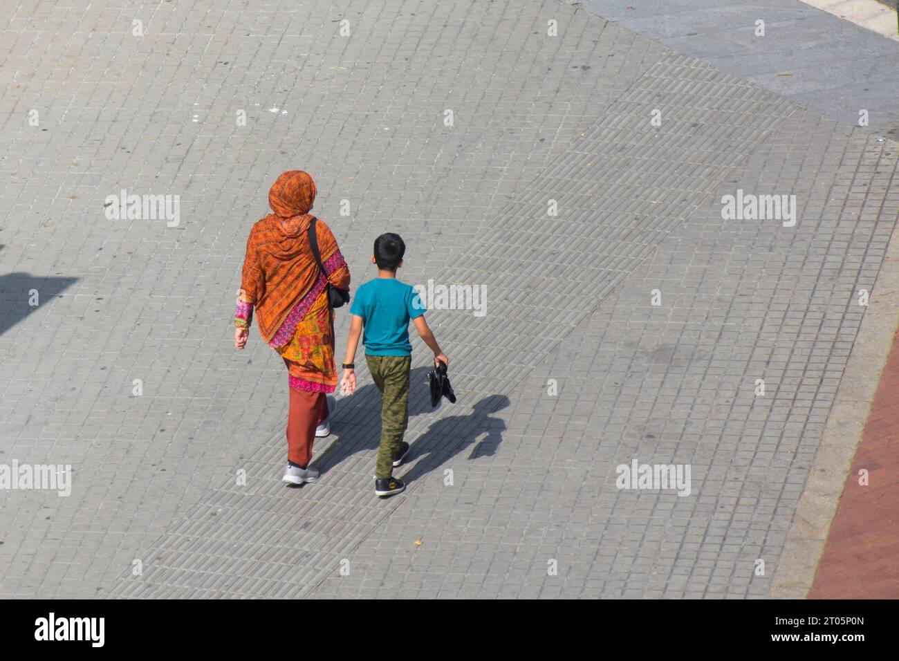 Muslimische Mutter, die mit ihrem Sohn auf der Straße läuft. Stockfoto