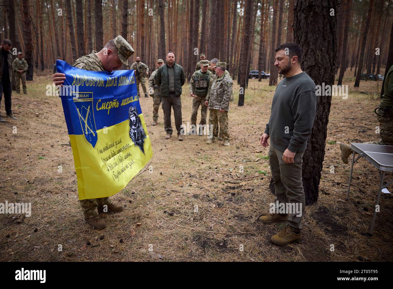 Kupjansk-Lyman, Ukraine. Oktober 2023. Der ukrainische Präsident Wolodymyr Zelenskyj, rechts, wird vom Befehlshaber der 25. Eigenständigen Luftlandebrigade „Sicheslav“ während eines Besuchs an den Frontlinien in der Region Charkiw am 3. Oktober 2023 in Kupjansk-Lyman, Ukraine, mit einer Kampfflagge versehen. Kredit: Ukrainischer Ratsvorsitz/Pressestelle Des Ukrainischen Präsidenten/Alamy Live News Stockfoto