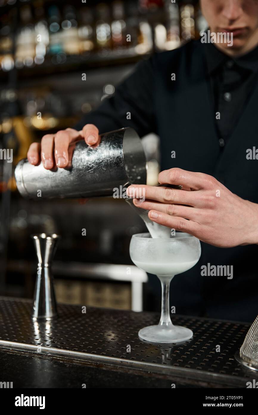 Blick auf den Barkeeper mit Cocktail-Shaker, der Milchpunsch in der Bar zubereitet, Cocktailkunst Stockfoto