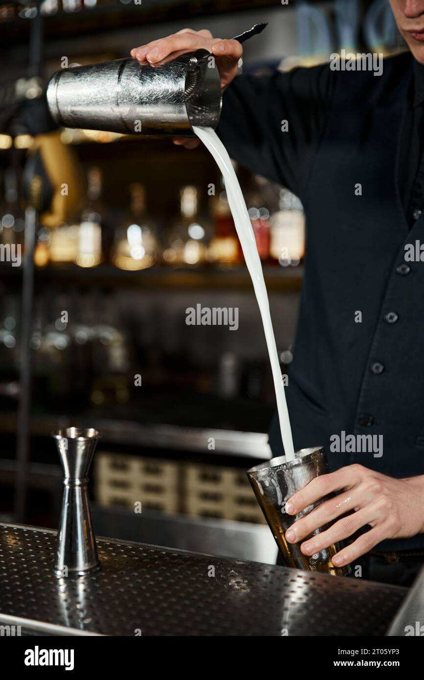 Blick auf den Barkeeper mit Cocktail-Shaker und Milchkrug, der in der Bar ein Craft-Getränk zubereitete Stockfoto