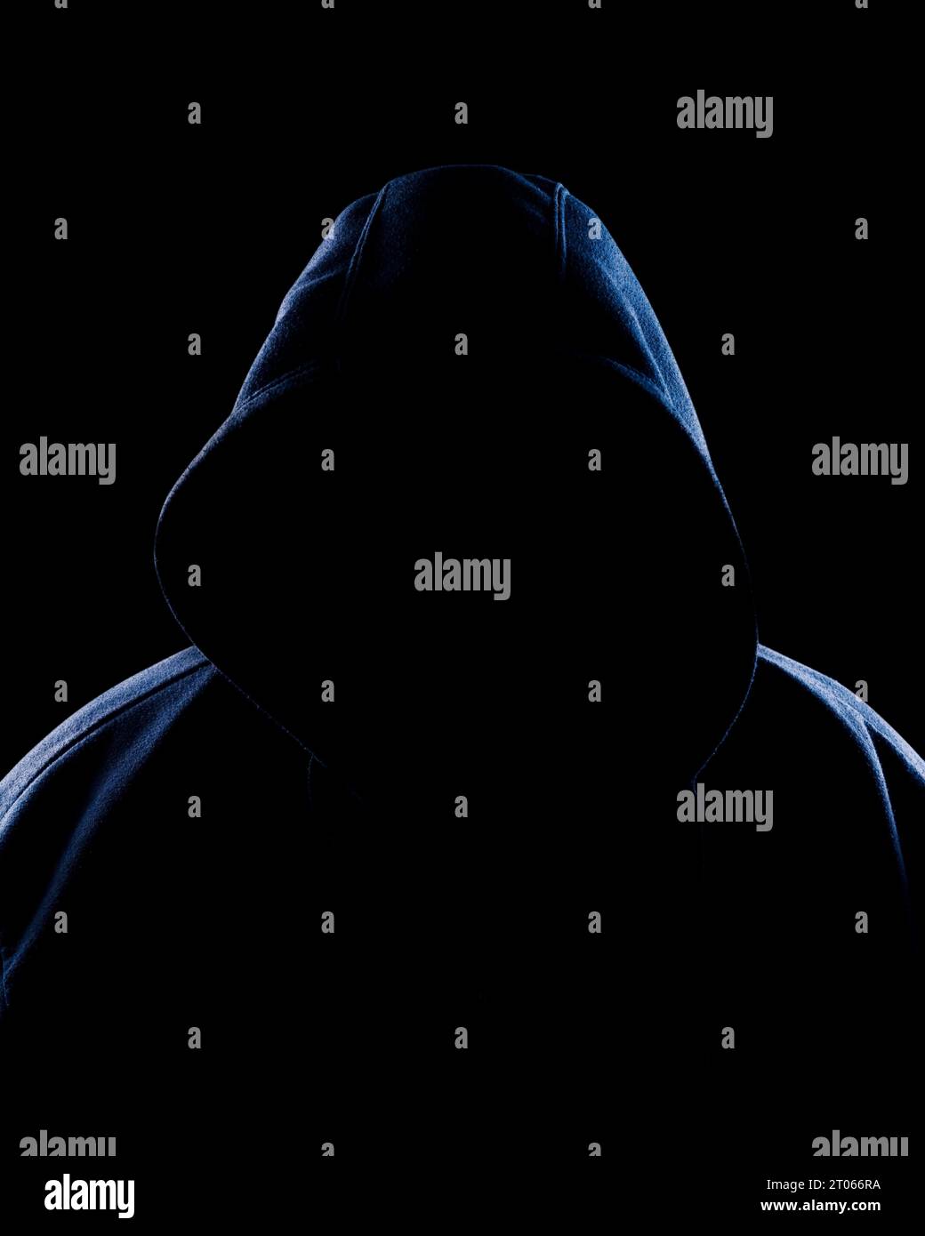 Eine Kapuzenfigur, die aus der Dunkelheit ragt Stockfoto