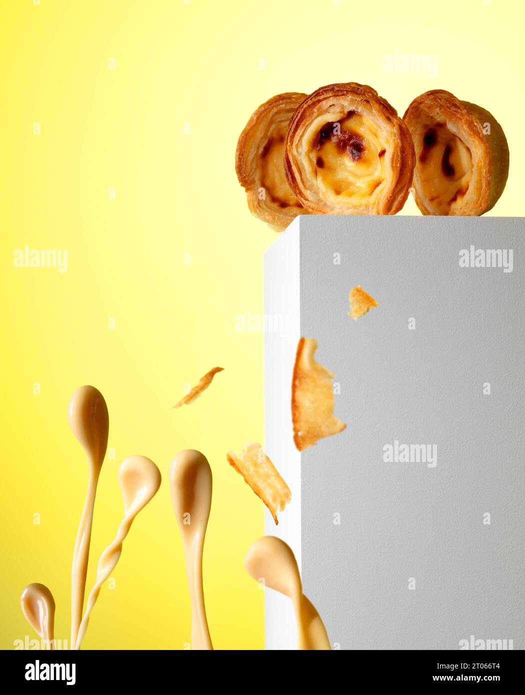 Drei Pastel de Nata Pustard Torten, die über den Rand in ein Pudding-Untergang blicken Stockfoto