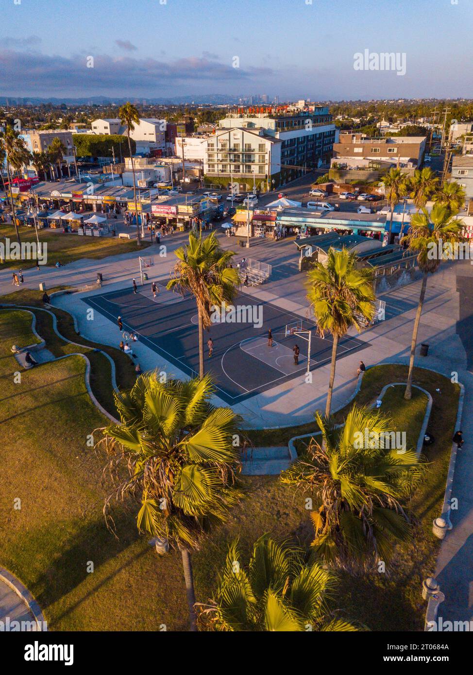 Luftaufnahmen mit einer Drohne während eines Winteruntergangs in Venice Beach, Los Angeles, Kalifornien, auf die Basketballfelder, Palmen und kurvige lan Stockfoto