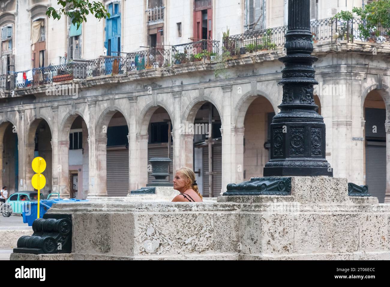 Eine Frau sitzt auf den Steinbänken des Paseo del Prado im Stadtzentrum der kubanischen Hauptstadt. Verwitterte Fassade von Gebäuden im Hintergrund Stockfoto