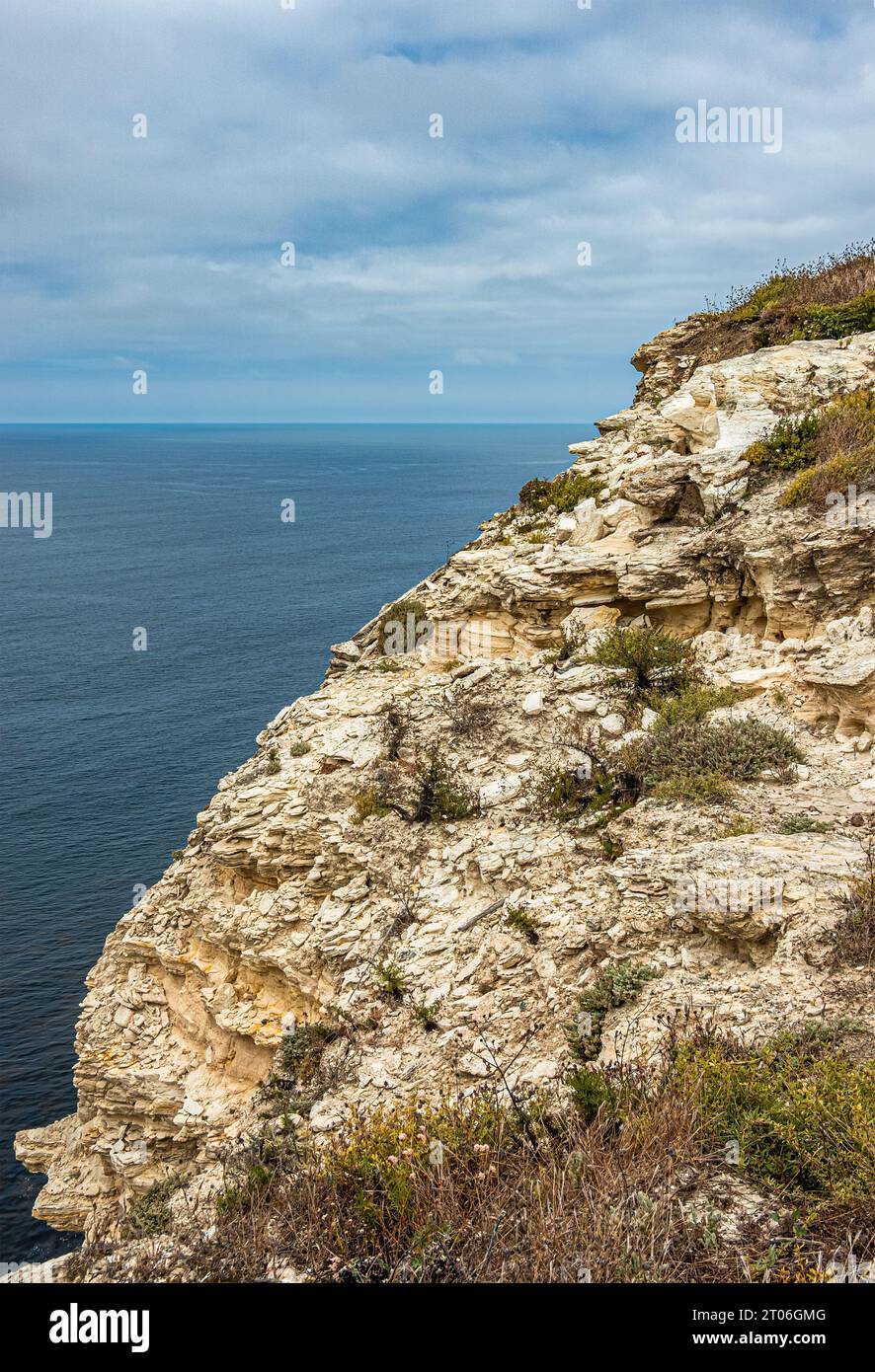 Santa Cruz Island, CA, USA - 14. September 2023: Die Klippe ist abbröckelnd und hat eine gelb-weiße Geologie mit dünn verteilten grünen Flecken. Blaue Wolke Stockfoto