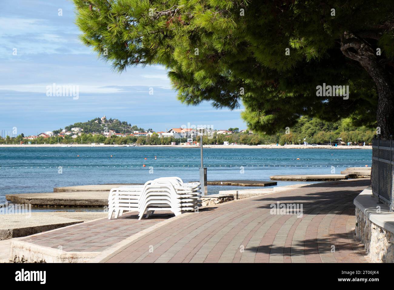Vodice, Kroatien - 24. September 2023: Leere Promenade mit Pinienbäumen am Strand und aufgestapelten Sonnenliegen am Ende der Saison Stockfoto