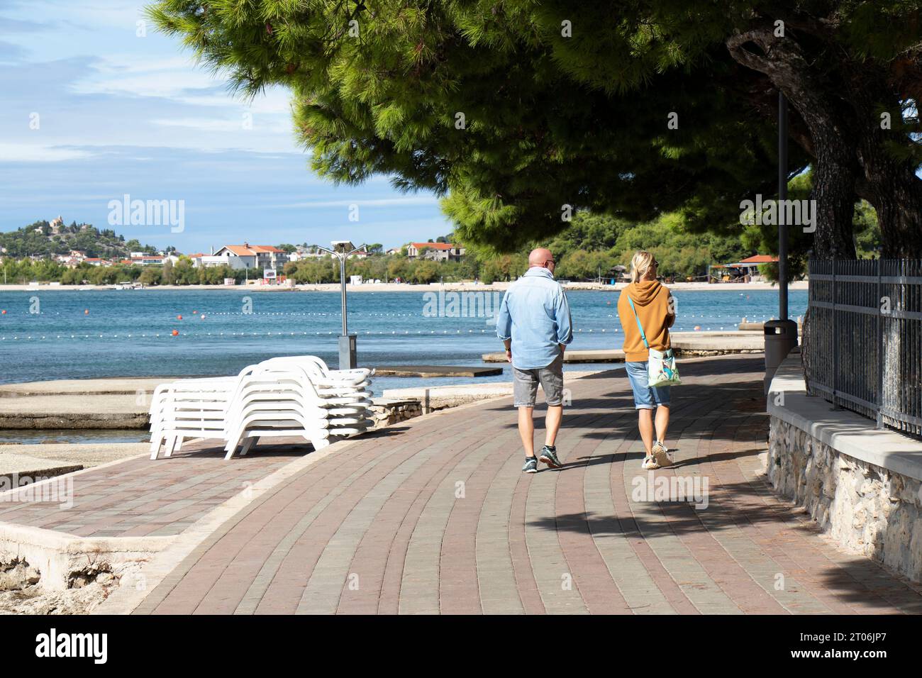 Vodice, Kroatien - 24. September 2023: Leute, die in der Nebensaison an der Promenade am Strand spazieren gehen, von hinten Stockfoto