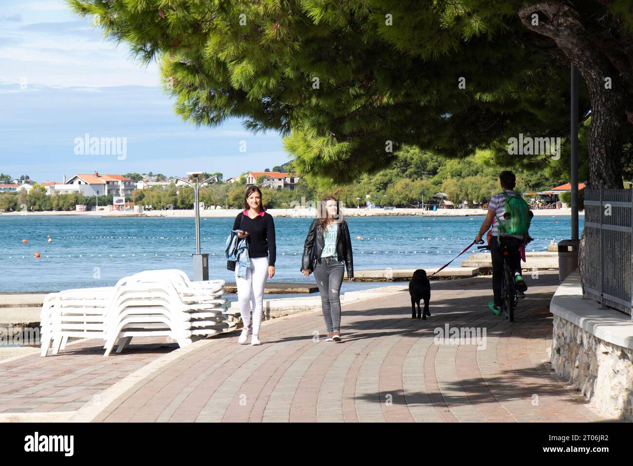 Vodice, Kroatien - 24. September 2023: Menschen wandern und radeln an der Promenade am Strand in der Nebensaison bei Sonnenuntergang Stockfoto