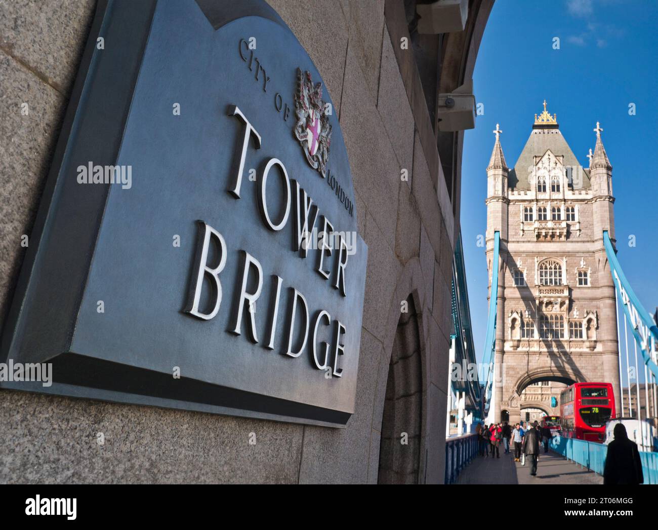 Tower Bridge River Themse London mit Namensschild im Vordergrund und Fußgängerweg über die Brücke mit traditionellem roten Londoner Bus und Verkehrsübergang. Southwark London Großbritannien Stockfoto