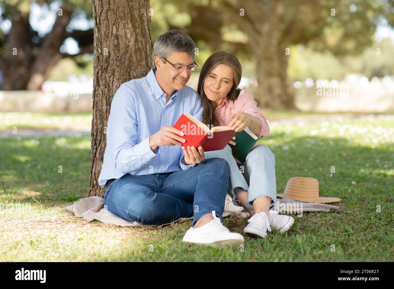 Reifes, romantisches Paar, das sich im Park entspannt und im Freien Bücher liest Stockfoto