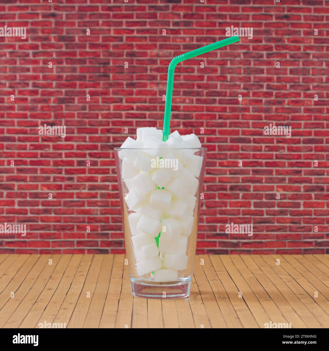 Kreative Komposition aus Glas voller Zuckerwürfel mit grünem Trinkstroh. Minimales ungesundes Ernährungskonzept. Seien Sie gesund Lifestyle Idee. Stockfoto