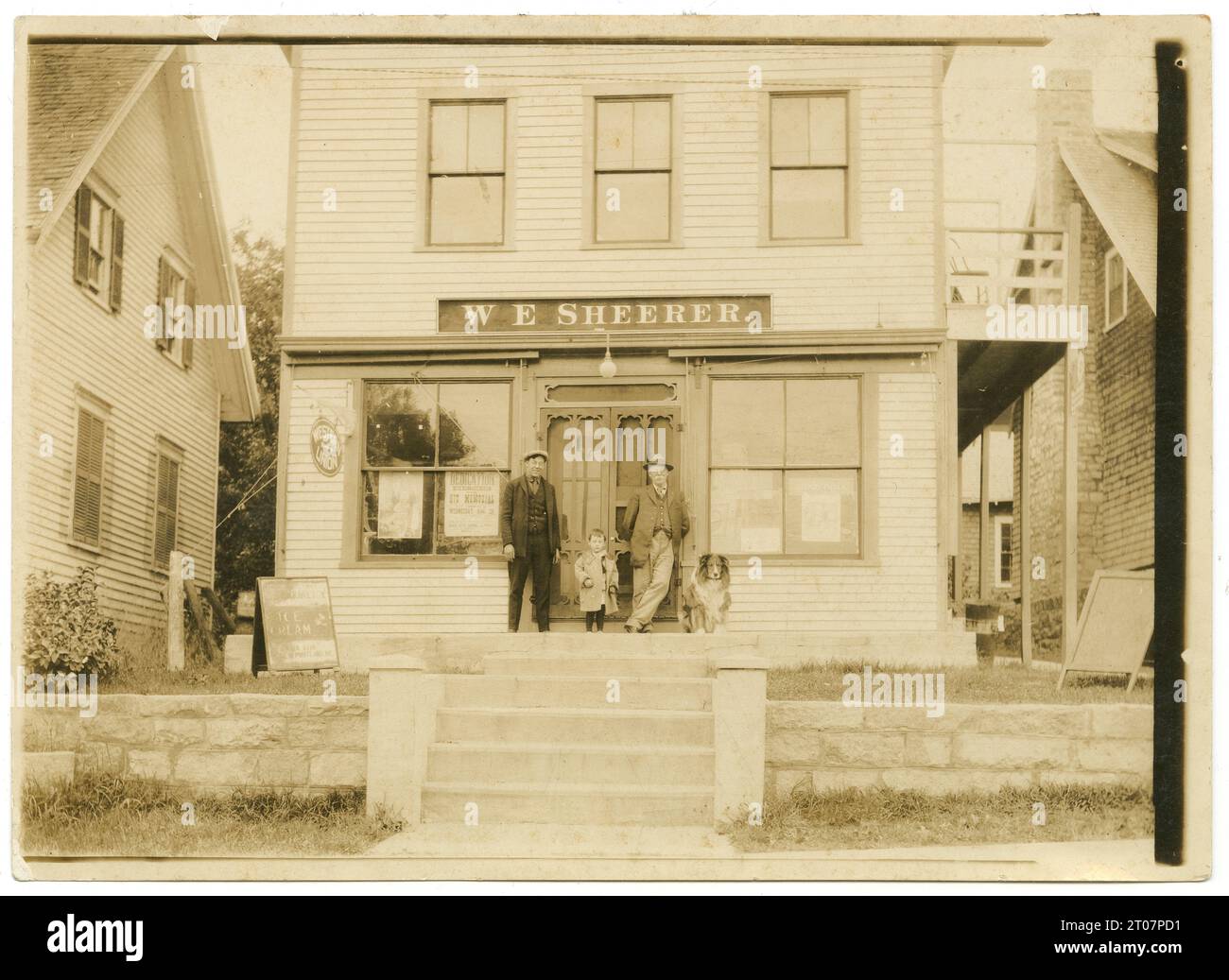 Antikes Foto von 1923, Ladenfront für W.E. Sheerer in Pächtern Harbor, St. George, Maine. Vermutlich zeigt er drei Familiengenerationen der Sheerer-Familie. Ein Poster im Fenster zeigt die Einweihung des Hix Memorial in South Thomaston, ME, die 1923 stattfand. QUELLE: ORIGINALFOTO Stockfoto