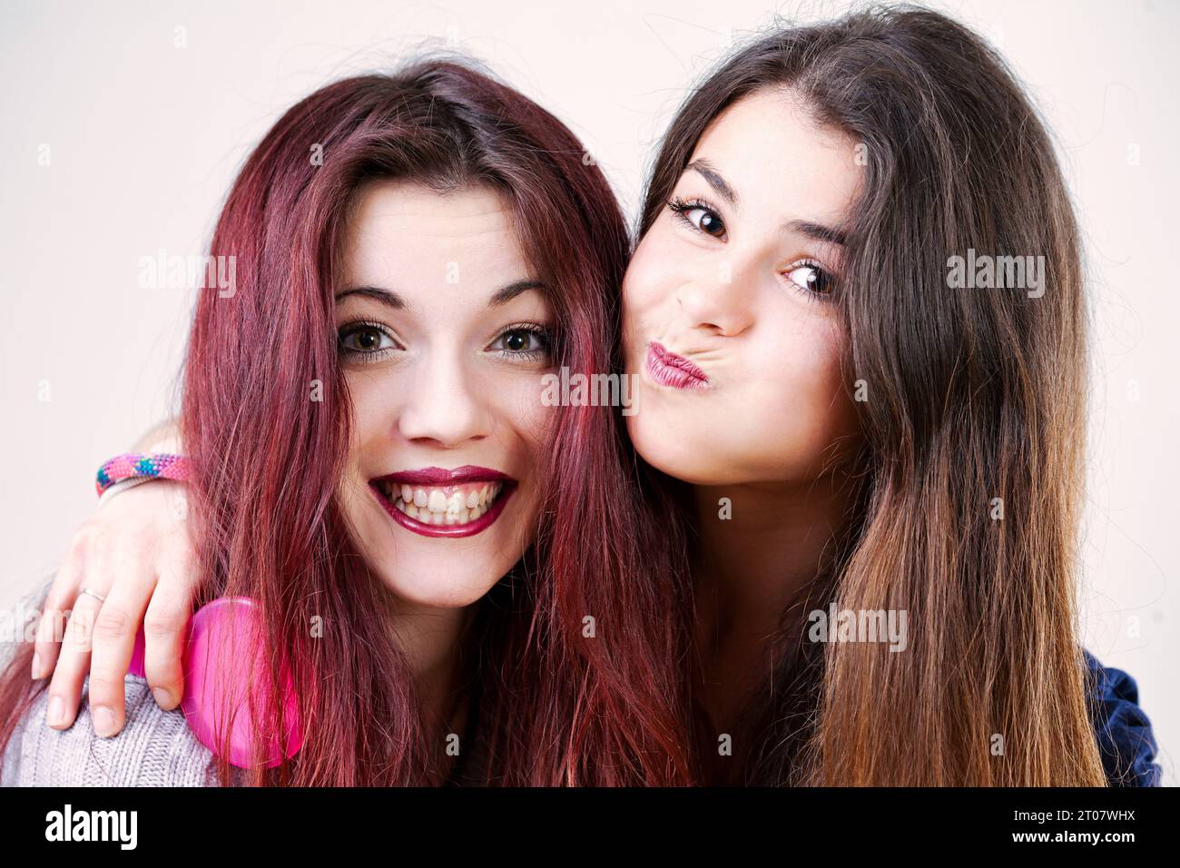 Porträt zweier verspielter junger Frauen, möglicherweise Schwestern oder Freunde, die lustige Gesichter machen. Mit gut geschminktem Make-up und langen Haaren sind sie auf die Dummheit vorbereitet Stockfoto