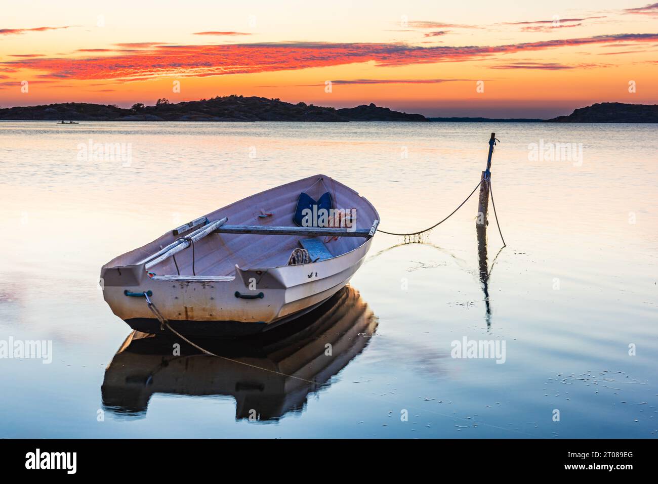 Verankertes Seeschiff bei Sonnenuntergang, reflektiert auf ruhigem Meereswasser. Stockfoto