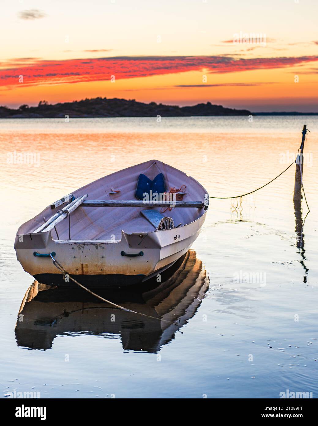 Verankertes Seeschiff bei Sonnenuntergang, reflektiert auf ruhigem Meereswasser. Stockfoto