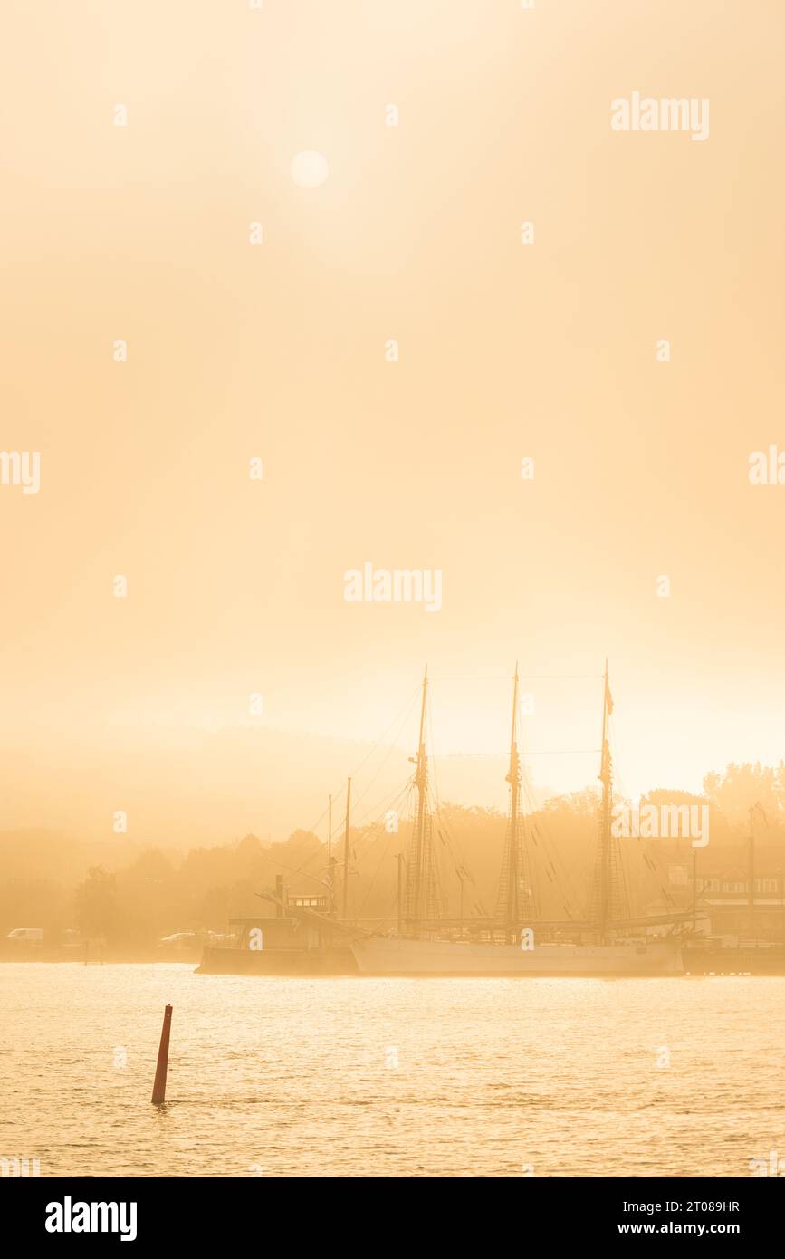 Ruhiger Sonnenaufgang über dem nebelverhangenen Hafen von Göteborg und dem Schiff. Stockfoto