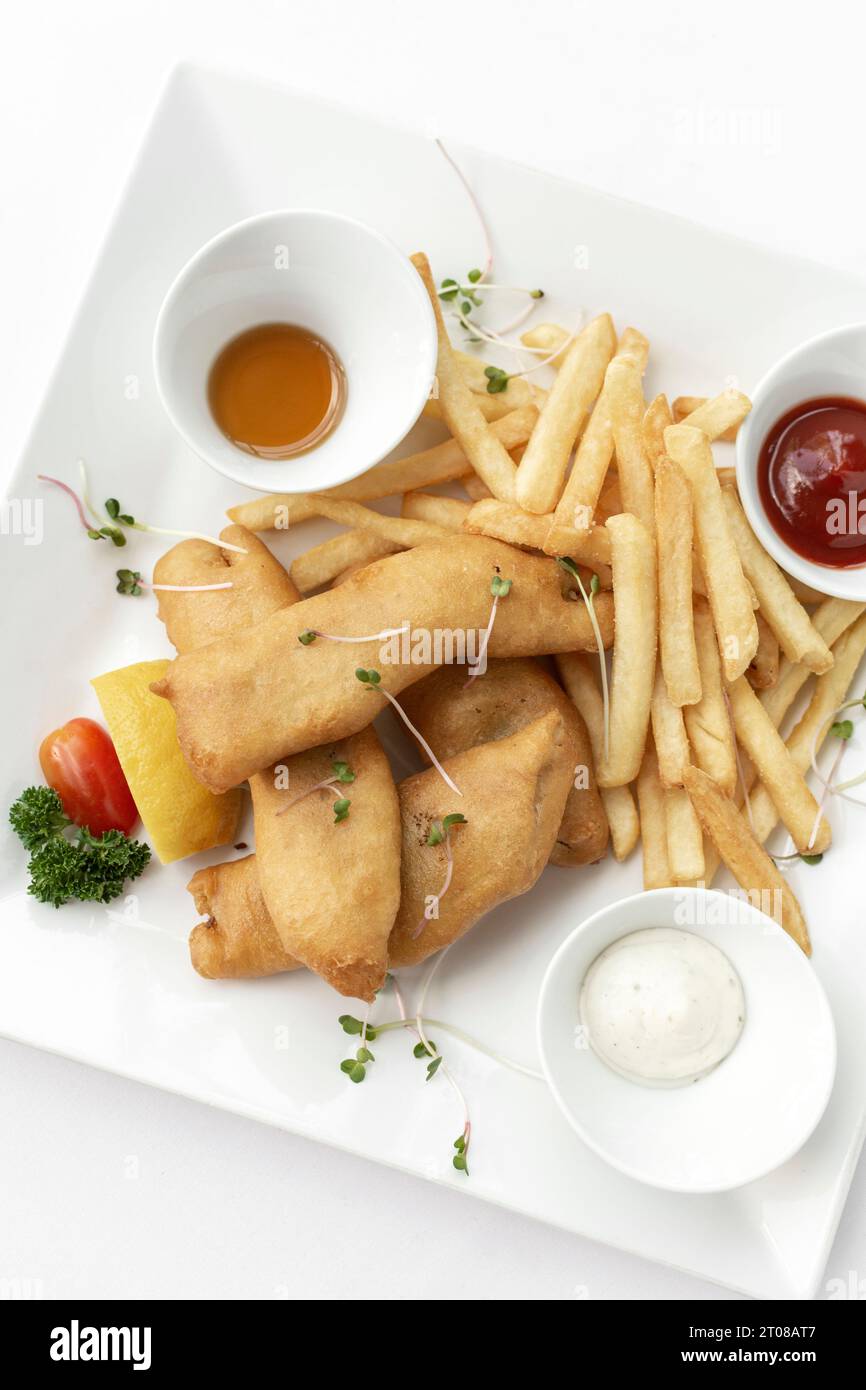 traditionelles englisches Fish-and-Chips-Essen im Restaurant auf weißem Teller und weißem Hintergrund Stockfoto