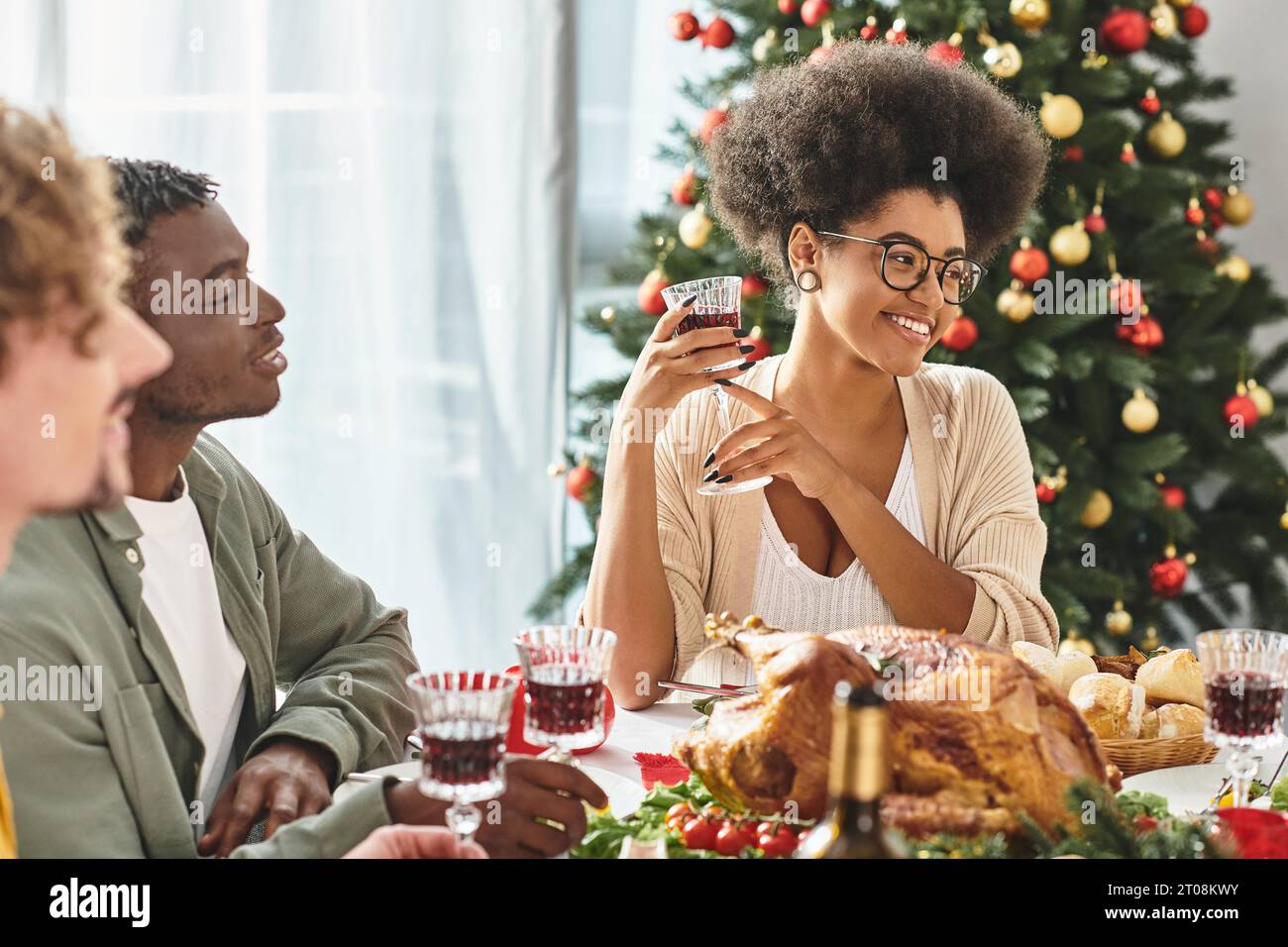 Multikulturelle Verwandte genießen Wein und Essen am Feiertagstisch und lächeln fröhlich, Weihnachten Stockfoto