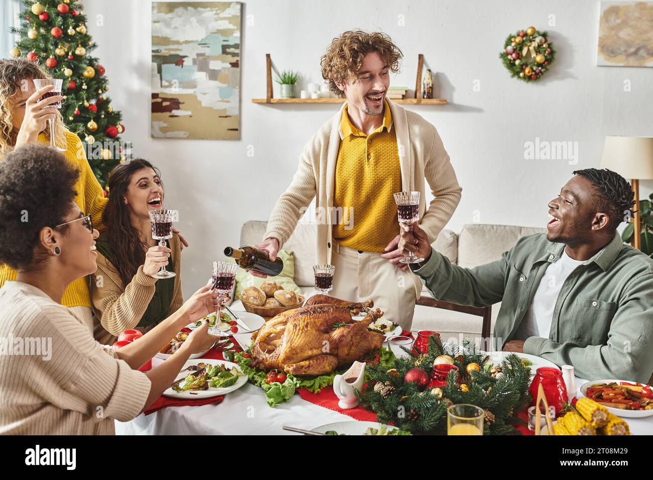 Große, fröhliche Familie mit mehreren Rassen, die viel Spaß hat, lachen und Wein trinken, am Weihnachtstag Stockfoto Große, fröhliche Familie mit mehreren Rassen, die viel Spaß hat, lachen und Wein trinken, am Weihnachtstag Stockfoto