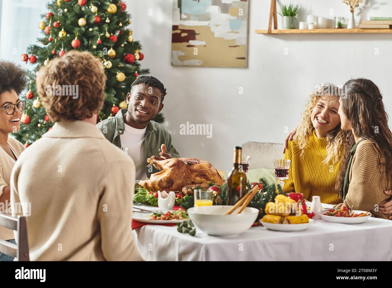 Junge multirassische Familie feiert Weihnachten zusammen am Feiertagstisch mit truthahn und Wein Stockfoto
